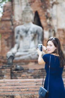 Asian woman photographing Buddha statue with cell phone
