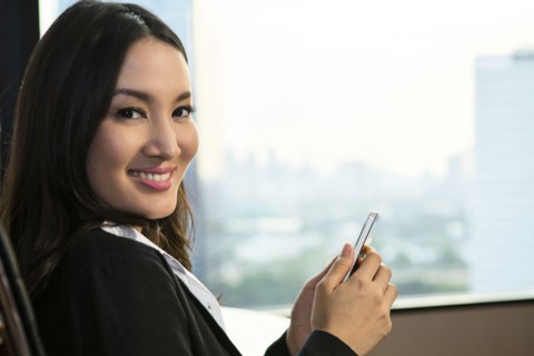 smiling Asian businesswoman texting on cell phone