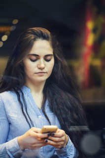 Serious Caucasian woman texting on cell phone