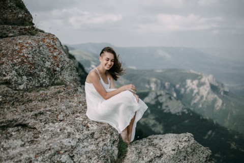 Smiling Caucasian woman sitting on rock overlooking landscape