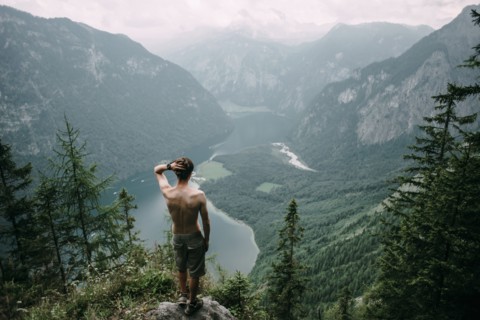 Caucasian man standing on rock overlooking lake in valley