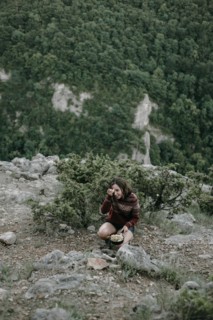 Smiling Caucasian woman crouching on mountain holding pan
