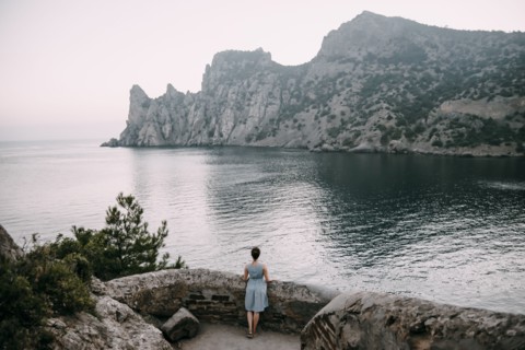 Caucasian woman standing at stone wall admiring ocean