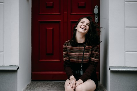 Laughing Caucasian woman sitting in doorway