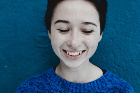 Smiling Caucasian woman near blue wall
