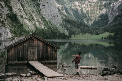 Caucasian man skipping stones in mountain lake