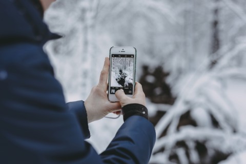 Caucasian woman photographing snow with cell phone