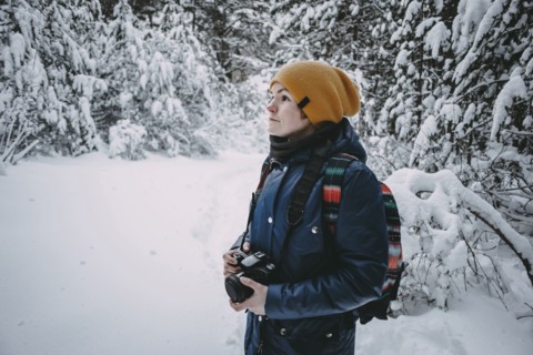 Caucasian woman holding camera in snowy forest