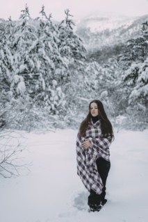 Caucasian woman wrapped in blanket in snowy forest