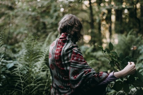 Caucasian woman holding green leaf in forest