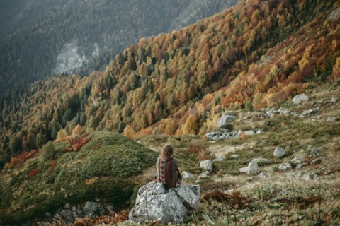 Caucasian woman sitting on mountain rock overlooking valley