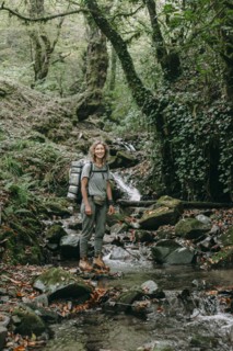 Caucasian woman backpacking across forest stream