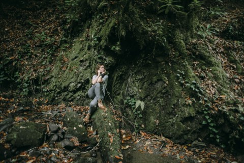 Caucasian woman sitting in forest holding branch