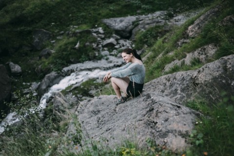 Smiling Caucasian woman sitting on rock on hill