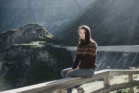 Pensive Caucasian woman sitting on wooden fence