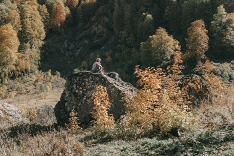 Caucasian woman sitting on boulder in autumn