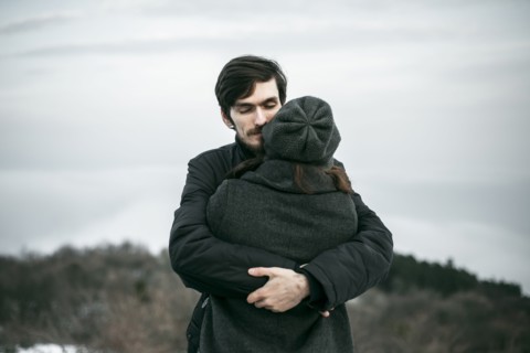 Caucasian couple hugging on hill