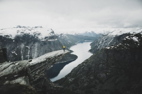 Caucasian man on cliff admiring scenic view of mountain river