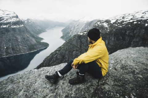 Caucasian man on cliff admiring scenic view of mountain river