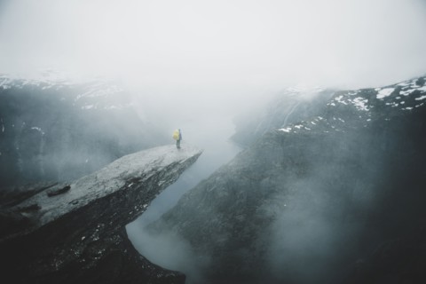 Caucasian man on foggy cliff admiring scenic view of mountain river