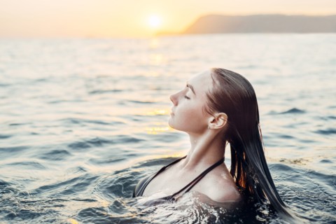 Caucasian woman swimming at sunset
