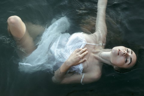 Caucasian woman wearing a dress floating in water