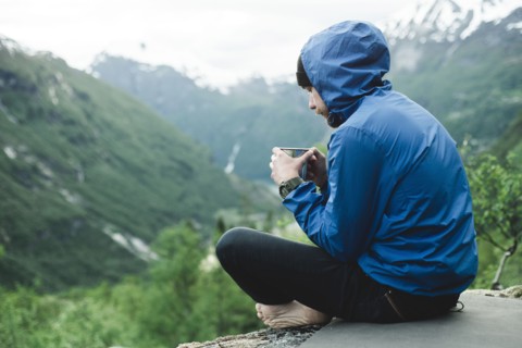 Caucasian man sitting in mountain landscape drinking coffee