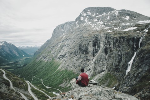 Caucasian man sitting on rock admiring scenic view of valley