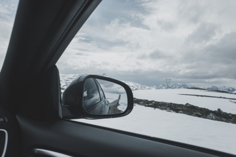 Car side-view mirror near winter landscape