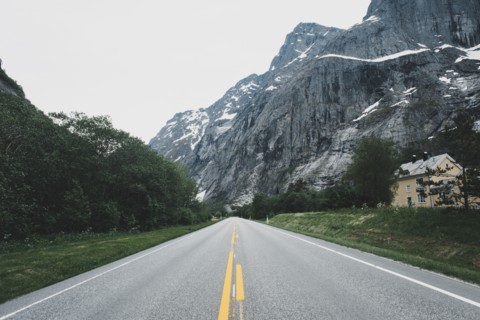House near empty road in mountain landscape