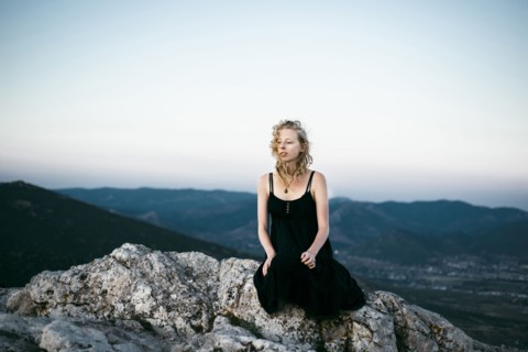 Caucasian woman sitting on rock near mountains