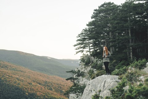 Caucasian woman standing on rock admiring scenic view of landscape