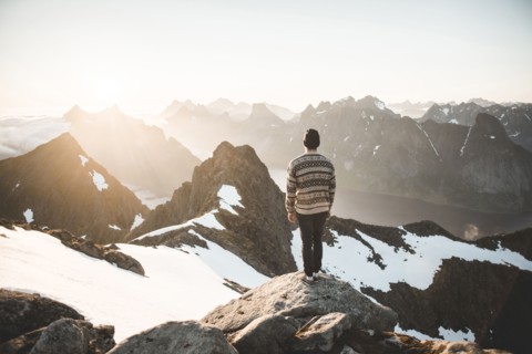 Caucasian man standing on rock admiring scenic view of mountain lake