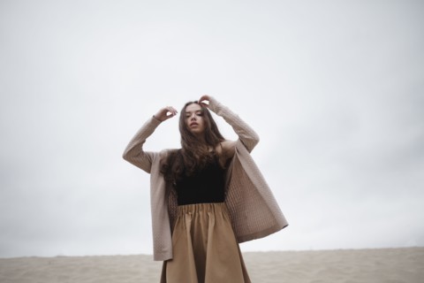 Caucasian woman standing with arms raised at beach