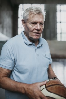 Portrait of serious Caucasian man holding basketball in gymnasium