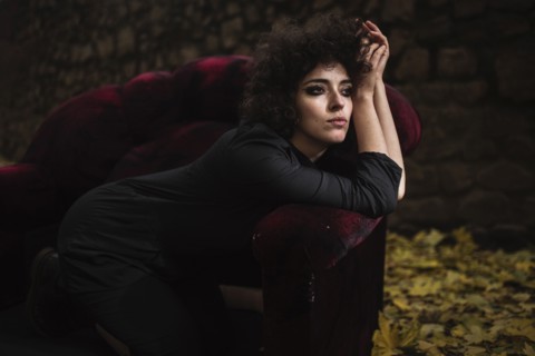 Pensive Caucasian woman laying on sofa outdoors
