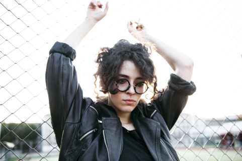 Pensive Caucasian woman leaning on chain-link fence