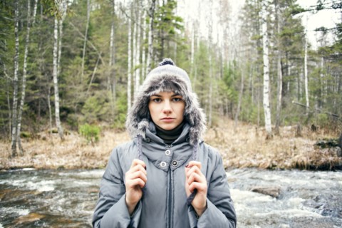 Caucasian woman in coat standing by rural river