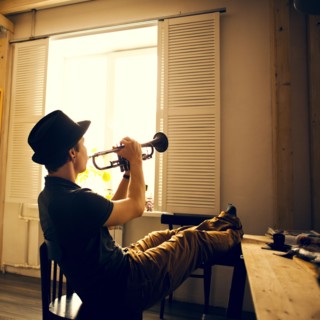 Caucasian man playing trumpet in kitchen
