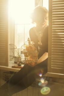 Caucasian woman holding birdcage in window