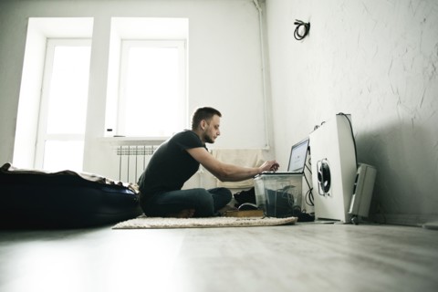 Caucasian man using laptop in bedroom