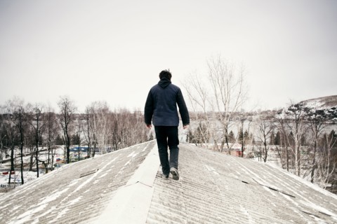 Caucasian man walking on snowy roof