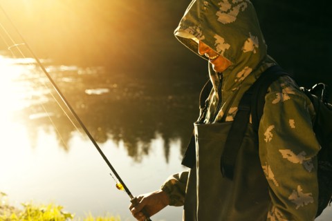 Mari man holding fishing rod at lake