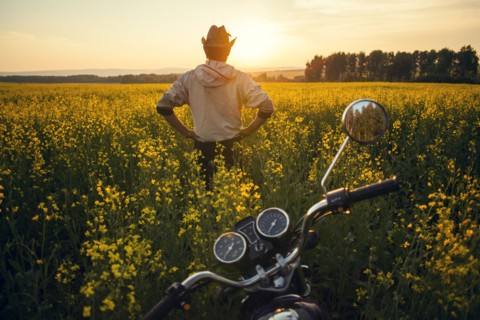Mari man standing near motorcycle in field of flowers