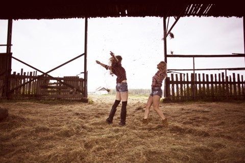 Caucasian women playing in hay in barn