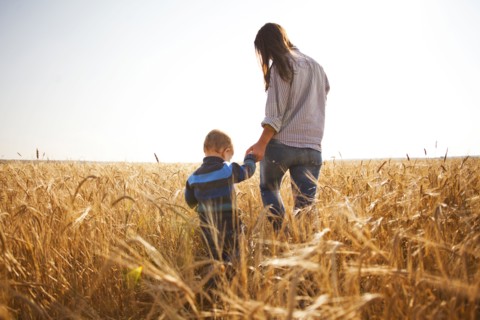 Caucasian mother and son walking in rural field