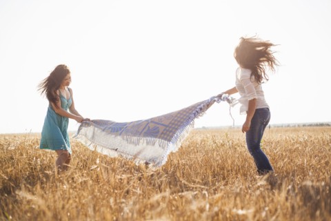 Caucasian women spreading blanket in rural field