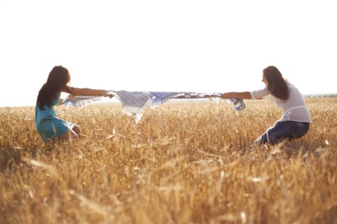 Caucasian women playing tug-of-war in rural field