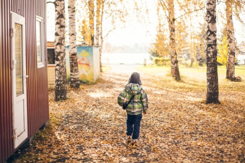 Mari boy walking in autumn leaves