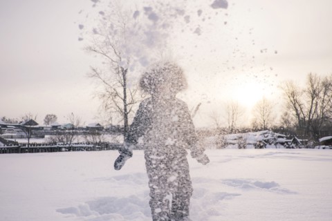 Mari boy in parka playing in snowy field